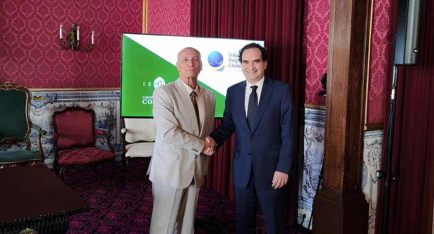 Dois homens de terno estão em pé, apertando as mãos e sorrindo para a câmera, em uma sala elegan...