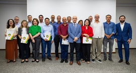 Foto de grupo institucional em plano aberto, mostrando cerca de 18 adultos, entre homens e mulhe...