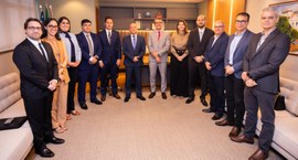 Uma fotografia em plano médio mostra um grupo de doze pessoas, sendo três mulheres e nove homens...