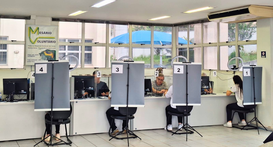 A imagem mostra uma sala de atendimento ao público bem iluminada e com grandes janelas ao fundo....