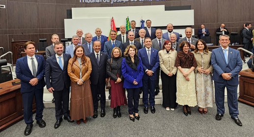 mostra um grupo de aproximadamente vinte e quatro pessoas reunidas para uma foto oficial em um a...
