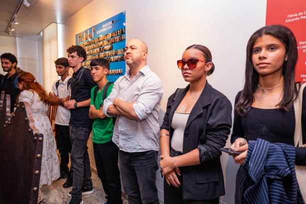 Estudantes da UEG visitam o TRE-GO Grupo de pessoas em pé, lado a lado, em um espaço interno que parece uma exposição ou galeria, o...