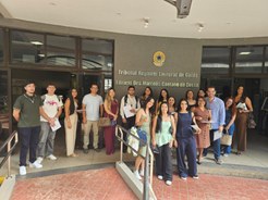 Um grupo de cerca de dezoito pessoas, composto por homens e mulheres jovens e adultos, posa para...