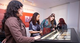 mostra um grupo de jovens visitando uma exposição cultural ou histórica em um ambiente interno e...