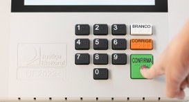 Foto mostra dedo indicador de uma mulher apertando a tecla verde "Confirma" na urna eletrônica