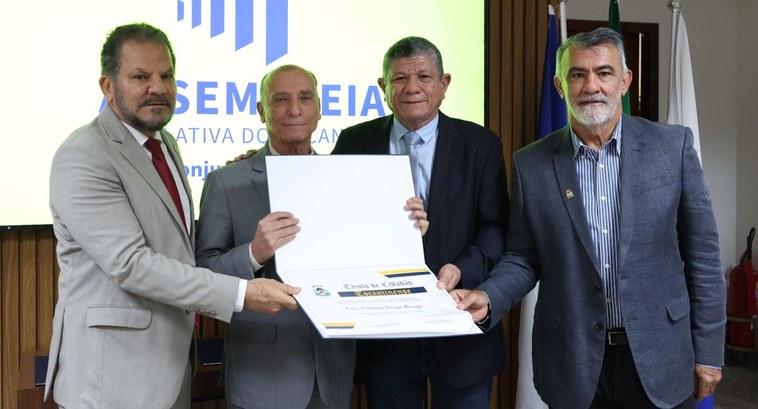 Presidente do TRE-GO é homenageado com Título de Cidadão no Tocantins Uma fotografia horizontal colorida de plano médio, em um ambiente interno bem iluminado, exibe q...