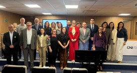 Uma fotografia horizontal em cores exibe um grupo de dezessete pessoas posando em pé em duas fil...