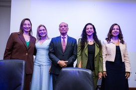 Fotografia de cinco pessoas adultas (quatro mulheres e um homem no centro) posando lado a lado e...
