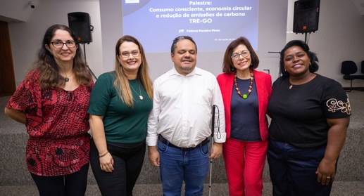 A imagem destaque.jpg mostra cinco pessoas posando sorridentes lado a lado em um auditório, posi...
