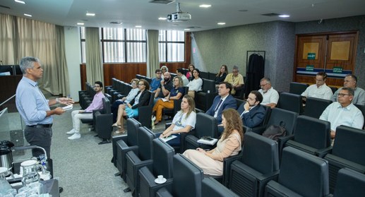 A imagem mostra uma sala de reuniões ou pequeno auditório durante uma apresentação ou treinament...