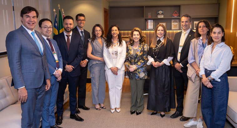 A imagem mostra onze pessoas em pé, lado a lado, posando para uma foto em grupo dentro de uma sa...
