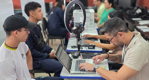 Em uma sala de aula adaptada para atendimento eleitoral, estudantes sentados em fila aguardam en...