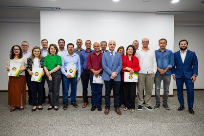 Foto de grupo institucional em plano aberto, mostrando cerca de 18 adultos, entre homens e mulhe...