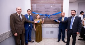 Cinco autoridades, quatro homens em trajes formais e uma mulher em um vestido dourado, posam lad...